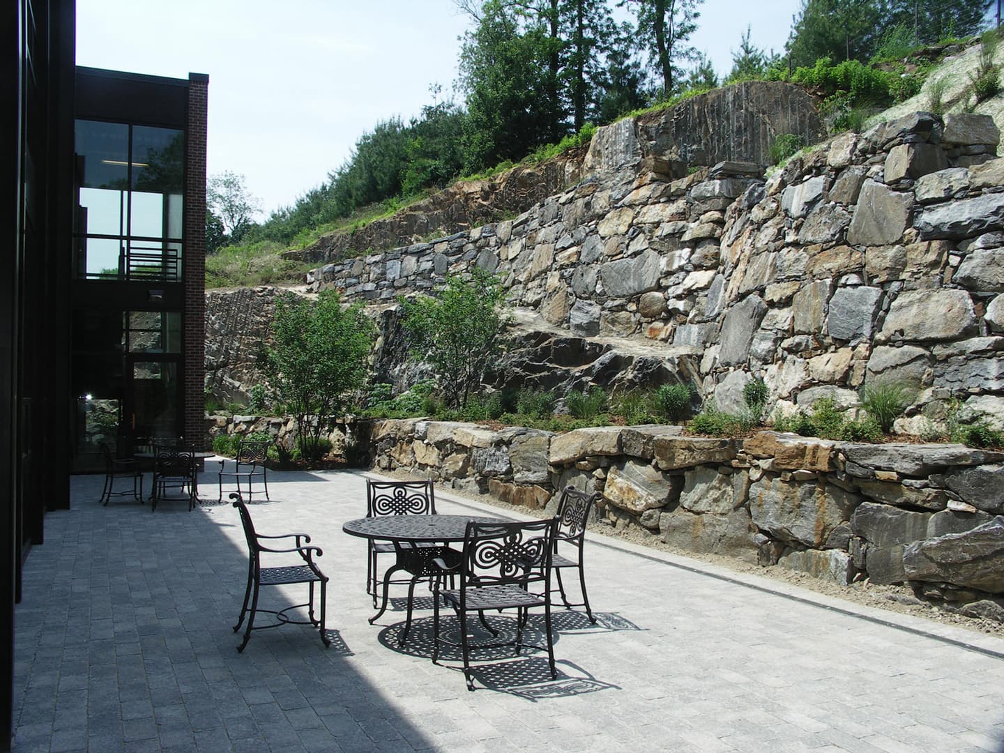 A landscaped outdoor terrace set against a natural stone retaining wall.